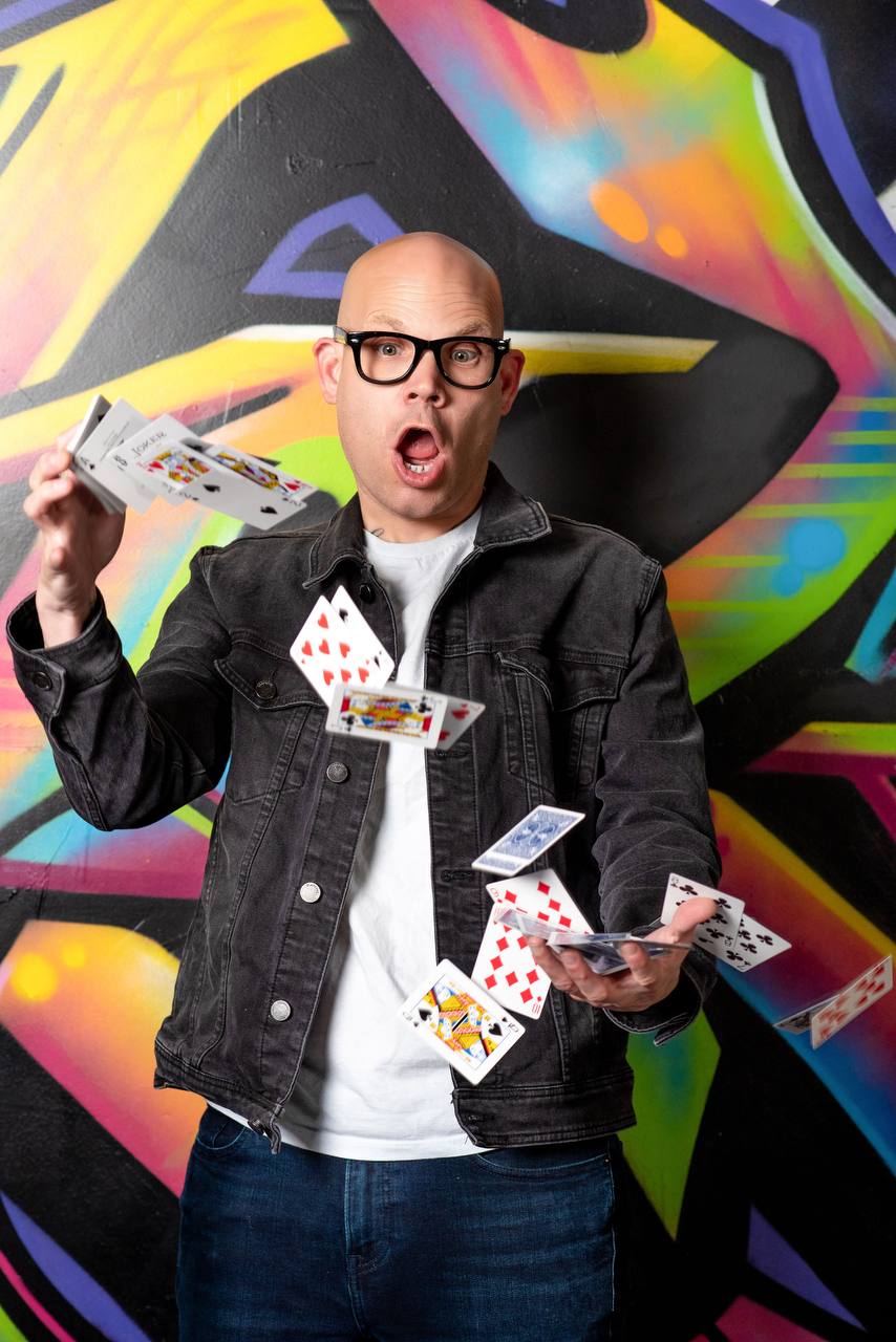 David Bonfadini holding playing cards in front of a graffiti wall