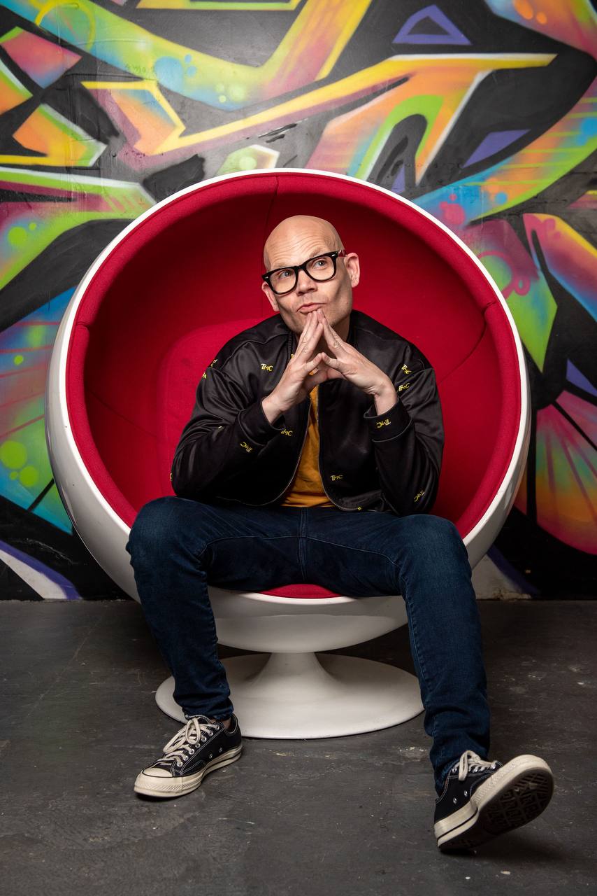 David Bonfadini seated in front of a graffiti wall