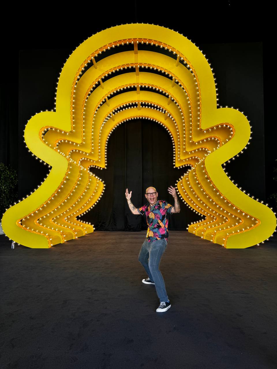 David Bonfadini standing beside a large yellow sculpture
